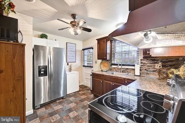 kitchen featuring island exhaust hood, stainless steel appliances, backsplash, sink, and ceiling fan