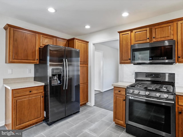 kitchen with appliances with stainless steel finishes, light hardwood / wood-style floors, and backsplash