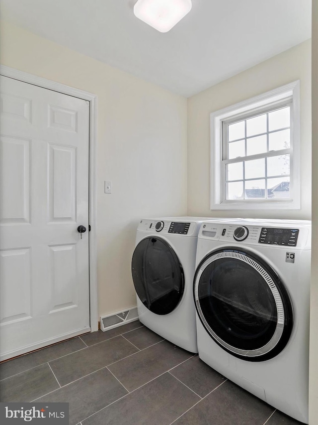 laundry area with washing machine and clothes dryer and dark tile patterned floors