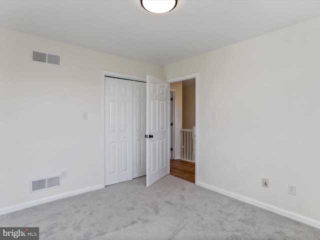 unfurnished bedroom featuring light carpet and a closet