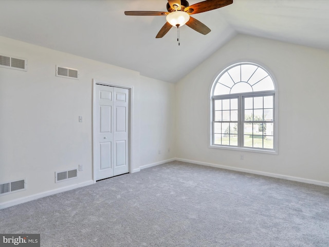 empty room featuring vaulted ceiling, light colored carpet, and ceiling fan