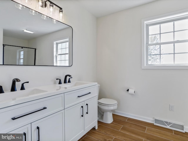 bathroom featuring toilet, an enclosed shower, a healthy amount of sunlight, and hardwood / wood-style flooring