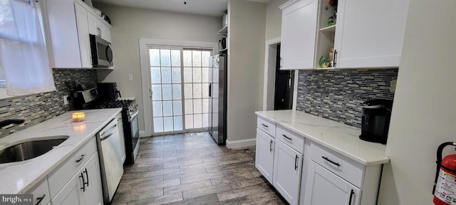 kitchen featuring sink, appliances with stainless steel finishes, light stone counters, and white cabinets