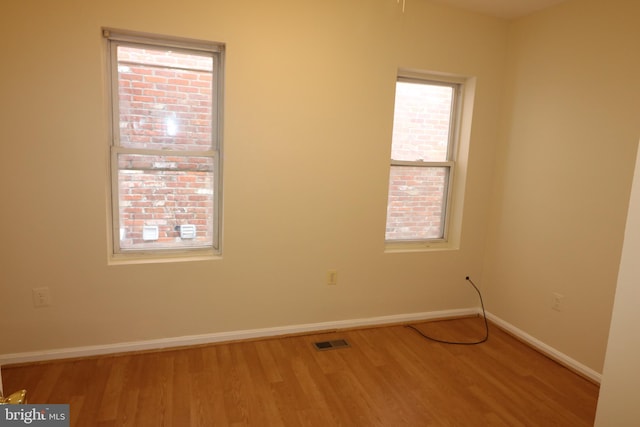 unfurnished room with hardwood / wood-style floors and a healthy amount of sunlight