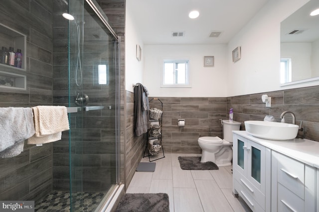 bathroom featuring vanity, tile walls, tile patterned flooring, toilet, and a shower with shower door