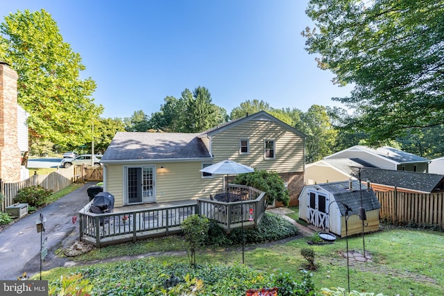 rear view of property featuring a shed, a wooden deck, and a yard