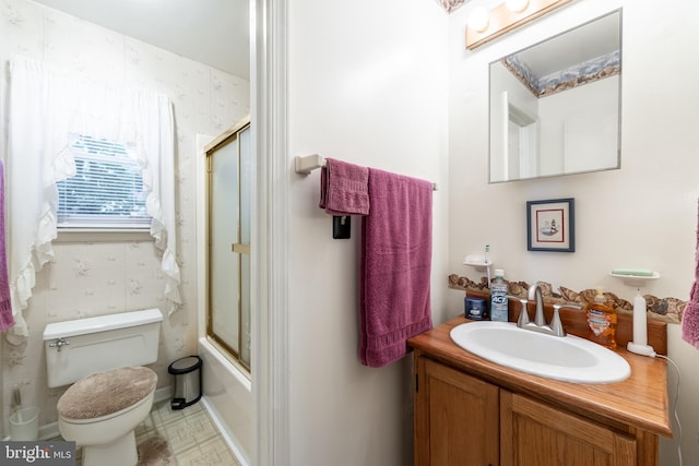 full bathroom featuring vanity, combined bath / shower with glass door, and toilet