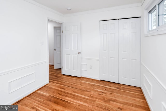 unfurnished bedroom featuring ornamental molding, light hardwood / wood-style flooring, and a closet