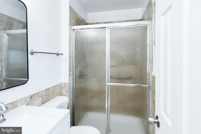 bathroom with vanity, toilet, and a shower with door