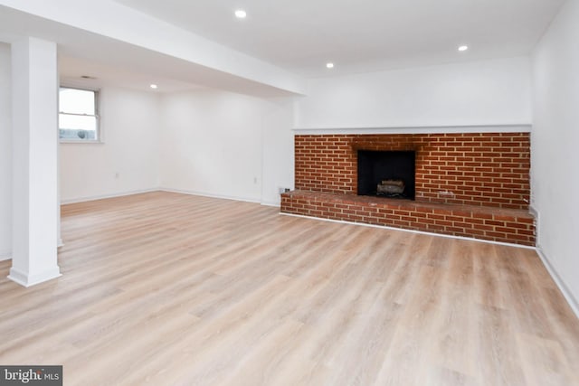 unfurnished living room featuring a brick fireplace and light hardwood / wood-style floors