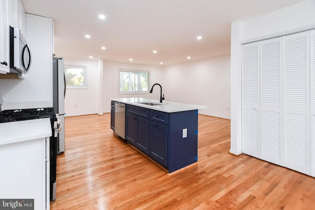 kitchen with light hardwood / wood-style flooring, stainless steel appliances, sink, and a kitchen island with sink