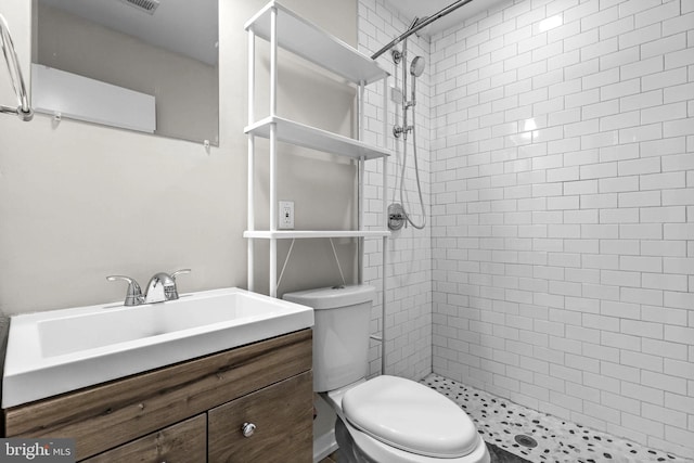 bathroom featuring vanity, toilet, and a tile shower