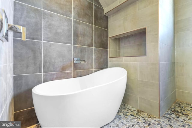 bathroom featuring a bathtub and tile walls