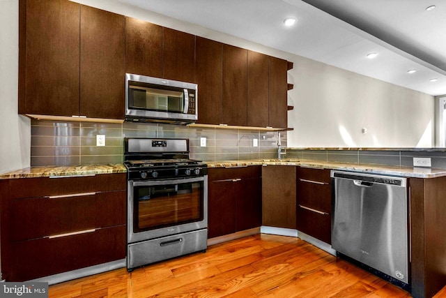 kitchen with decorative backsplash, light hardwood / wood-style floors, light stone counters, and appliances with stainless steel finishes