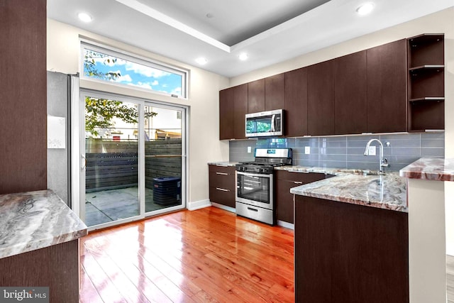 kitchen featuring light stone countertops, dark brown cabinetry, stainless steel appliances, sink, and light hardwood / wood-style flooring