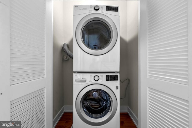 laundry room with stacked washer / drying machine and dark wood-type flooring