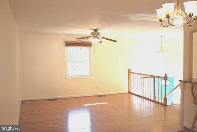 unfurnished room with hardwood / wood-style floors and ceiling fan with notable chandelier