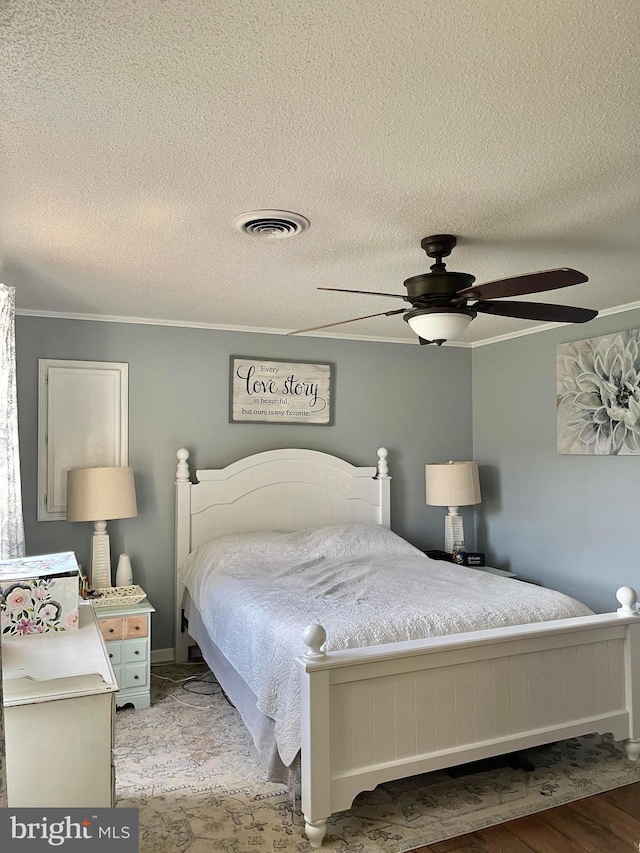 bedroom featuring ornamental molding, light hardwood / wood-style flooring, a textured ceiling, and ceiling fan