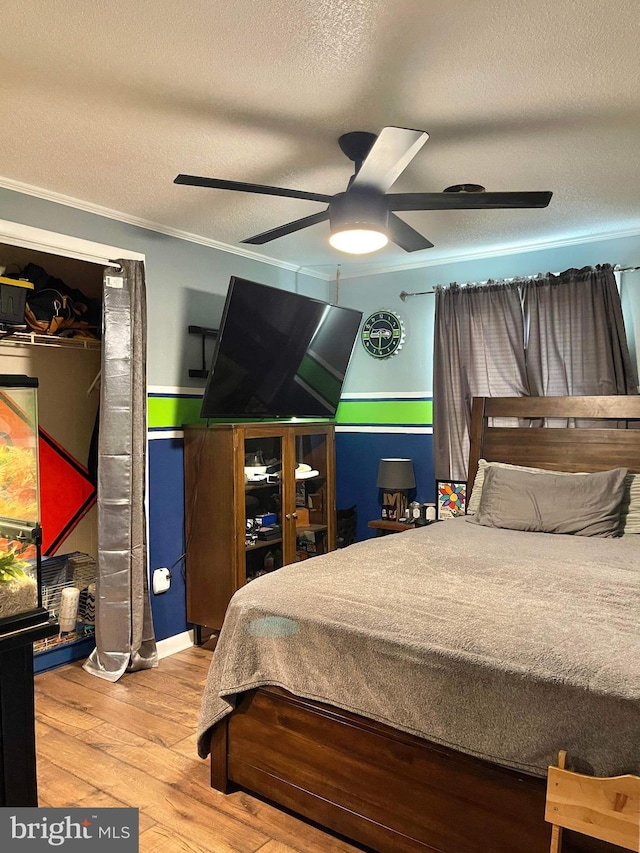 bedroom featuring a textured ceiling, crown molding, wood-type flooring, and ceiling fan