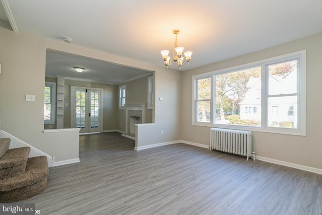 unfurnished living room with radiator, a healthy amount of sunlight, and wood-type flooring