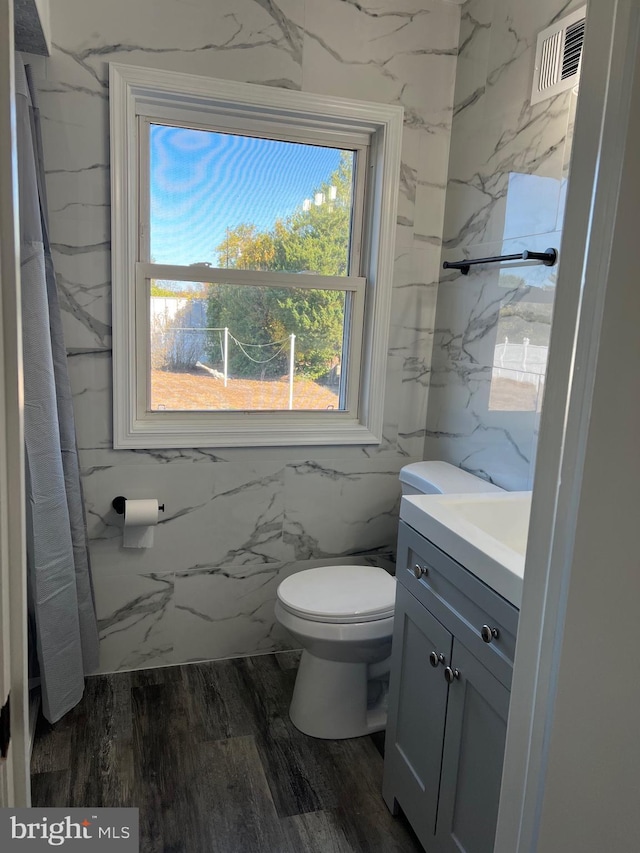 bathroom featuring vanity, hardwood / wood-style flooring, toilet, and tile walls