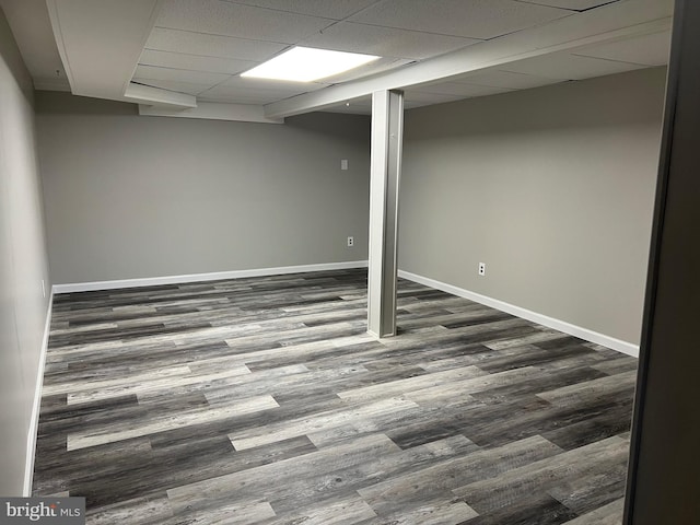 basement featuring a paneled ceiling and dark hardwood / wood-style floors