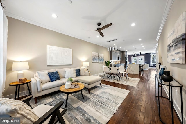 living room with ceiling fan with notable chandelier, ornamental molding, and dark hardwood / wood-style flooring