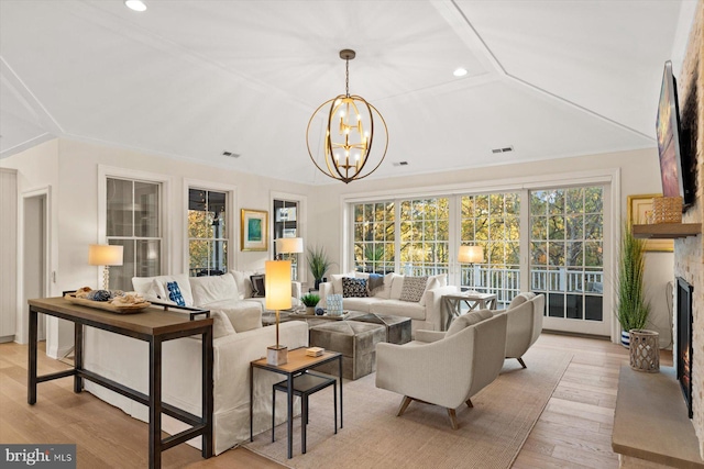 living room with an inviting chandelier, light hardwood / wood-style floors, vaulted ceiling, and a wealth of natural light