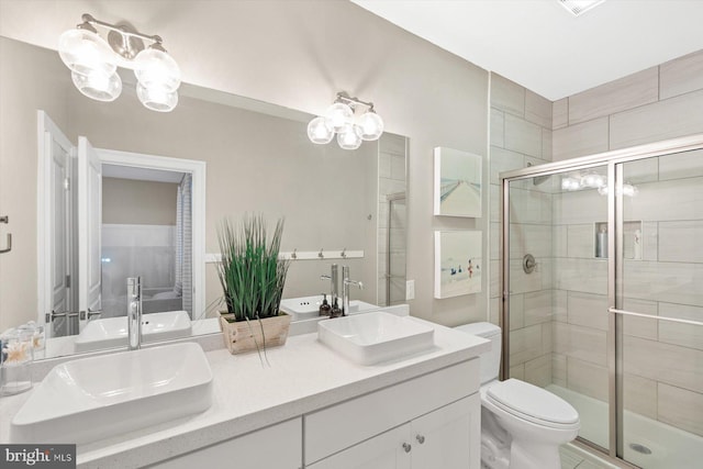 bathroom with a shower with door, vanity, and toilet