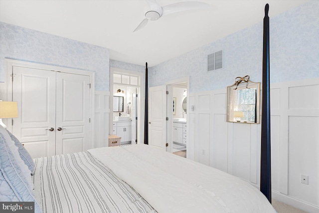 bedroom featuring a closet, ensuite bathroom, ceiling fan, and carpet floors