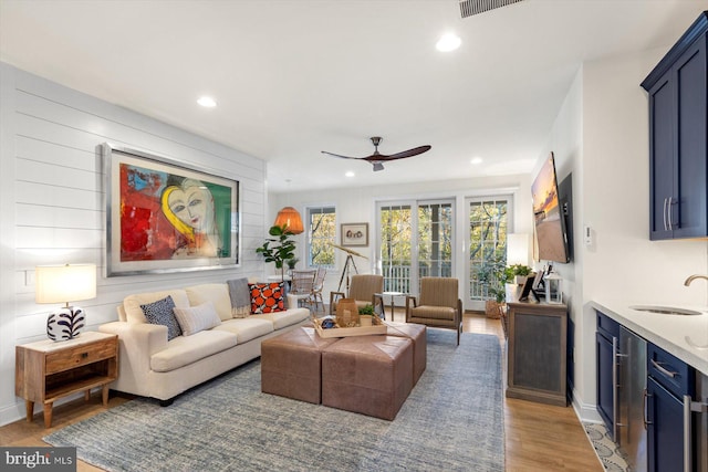 living room with ceiling fan, sink, and light hardwood / wood-style floors