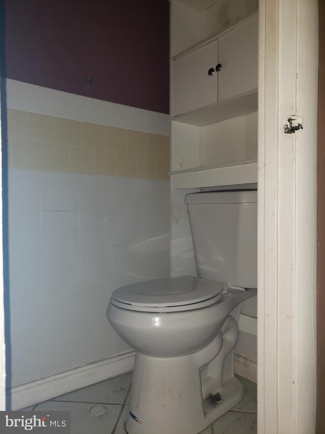 bathroom with toilet and tile walls