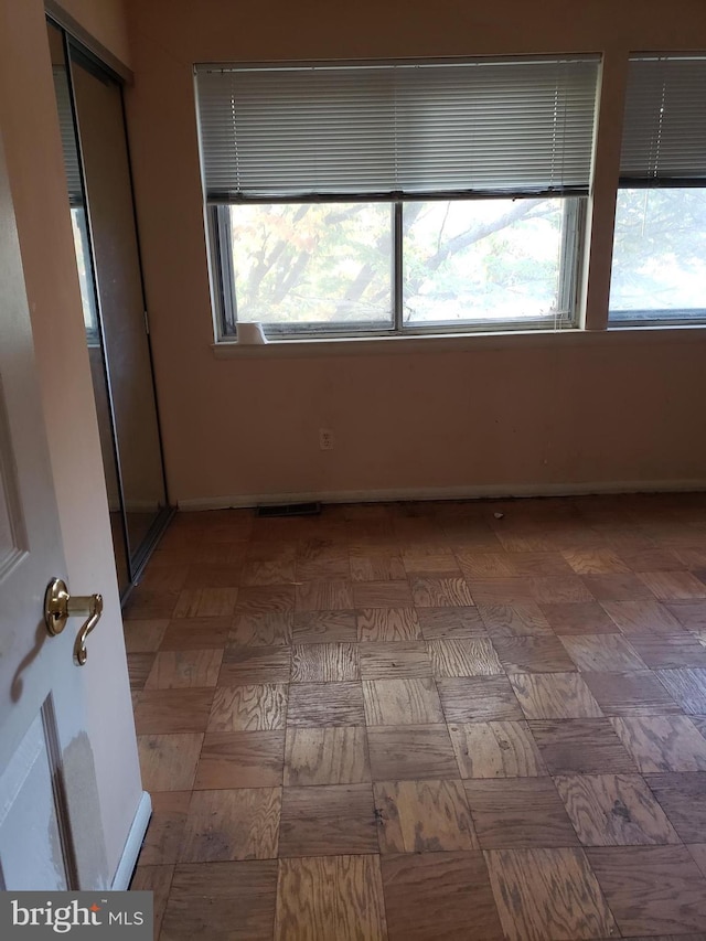 empty room with baseboards, a wealth of natural light, and visible vents