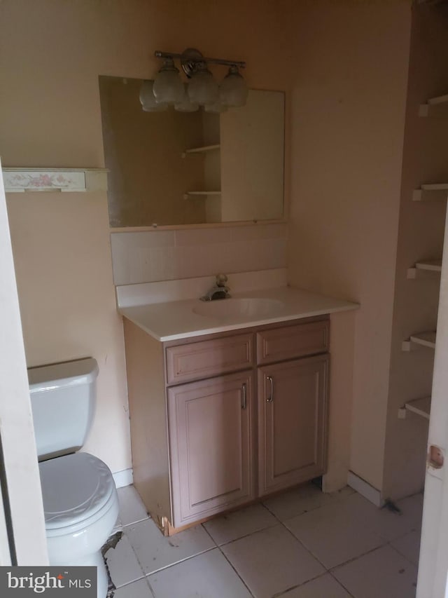 bathroom with toilet, tile patterned floors, and vanity