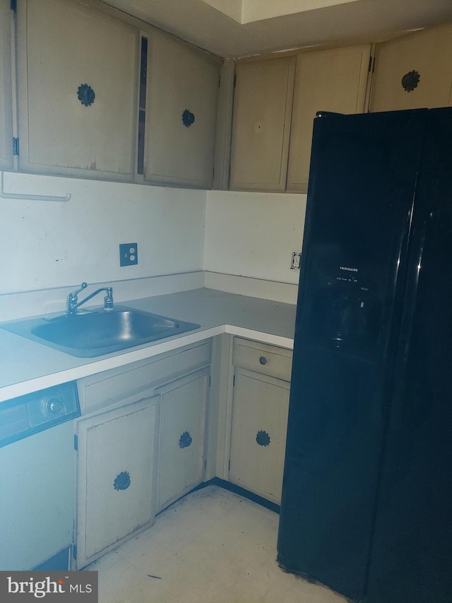 kitchen featuring black fridge, a sink, light countertops, and white dishwasher