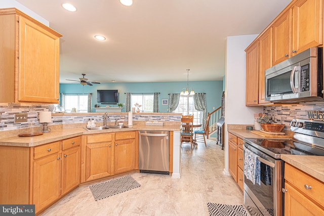 kitchen featuring a wealth of natural light, sink, stainless steel appliances, and decorative light fixtures