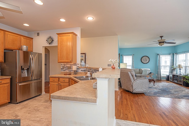 kitchen featuring ceiling fan, sink, stainless steel fridge with ice dispenser, kitchen peninsula, and light wood-type flooring