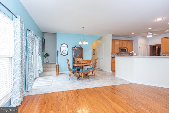 dining area with light hardwood / wood-style flooring and ceiling fan with notable chandelier