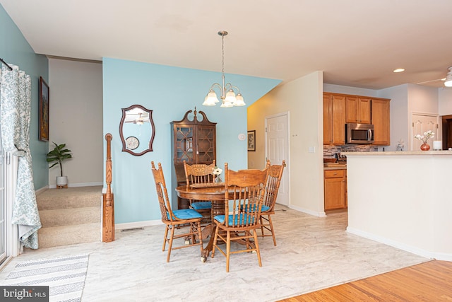 dining space with light hardwood / wood-style floors and ceiling fan with notable chandelier