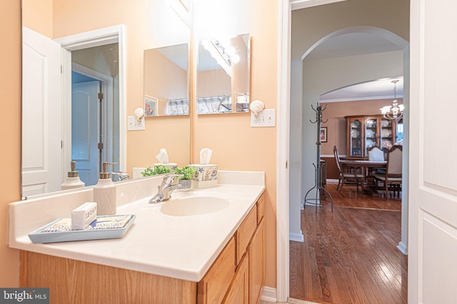 bathroom with vanity, wood-type flooring, ornamental molding, and a chandelier