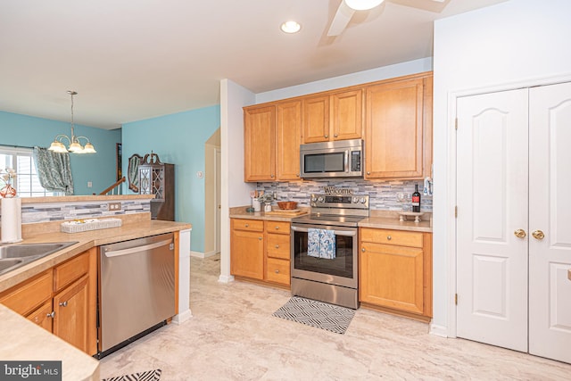 kitchen with backsplash, hanging light fixtures, stainless steel appliances, and ceiling fan with notable chandelier