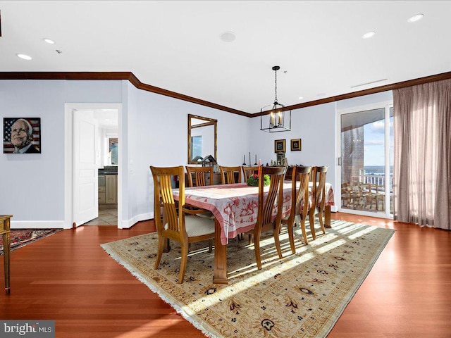 dining space featuring crown molding, hardwood / wood-style floors, and a notable chandelier