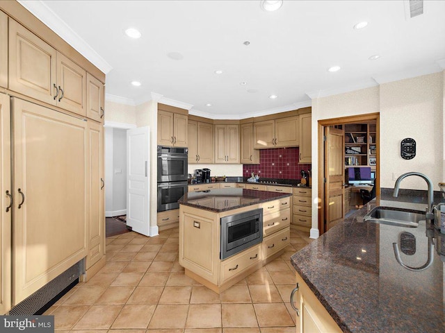 kitchen with sink, appliances with stainless steel finishes, a center island, ornamental molding, and dark stone counters