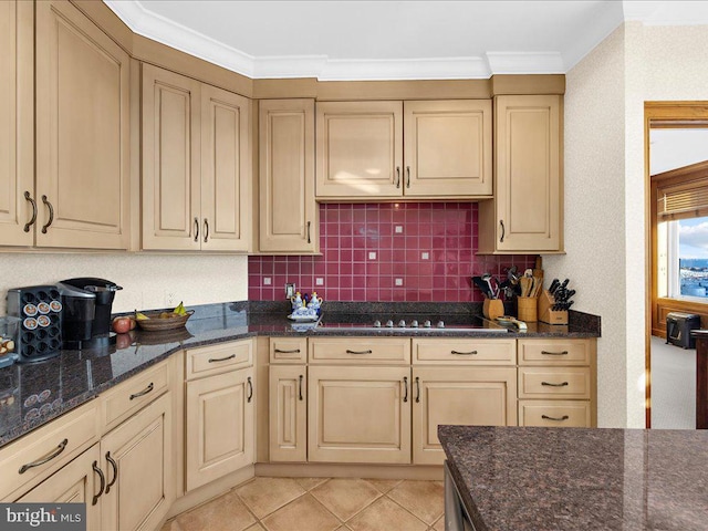 kitchen featuring tasteful backsplash, dark stone counters, light tile patterned floors, crown molding, and black cooktop