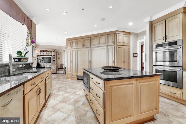 kitchen with ornamental molding, dark stone counters, stainless steel appliances, sink, and a center island