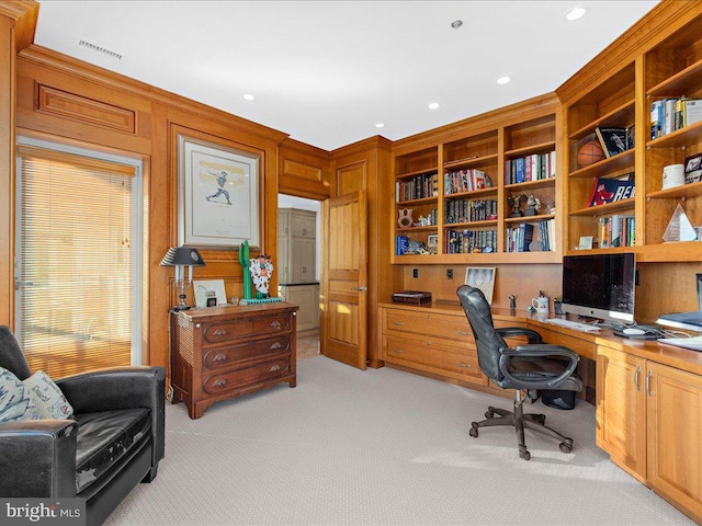 carpeted home office featuring ornamental molding and built in desk