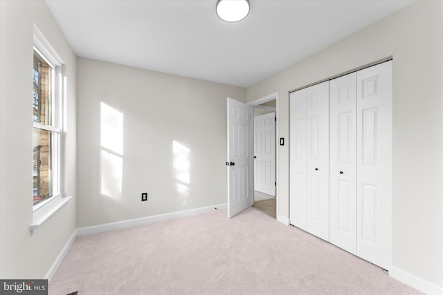 unfurnished bedroom with a closet, light carpet, and multiple windows