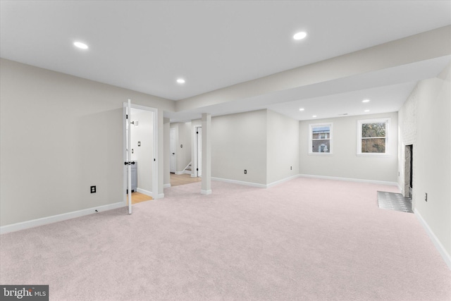 basement featuring light colored carpet and a brick fireplace