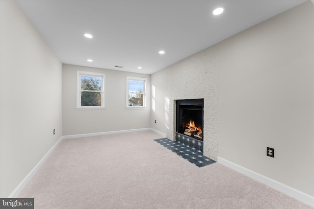 unfurnished living room with a large fireplace and light colored carpet