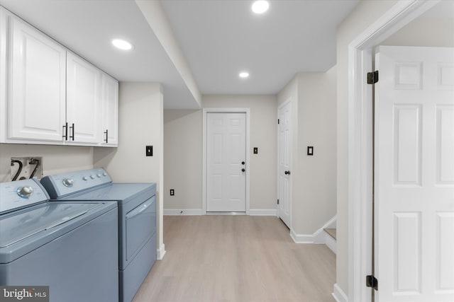 clothes washing area with washing machine and dryer, cabinets, and light wood-type flooring